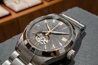 Gros plan d'une montre de luxe suisse mécanique sur ardoise grise, cadran guilloché en or et mouvement apparent sous verre saphir